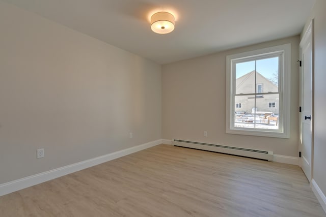 empty room featuring light wood-type flooring and a baseboard heating unit