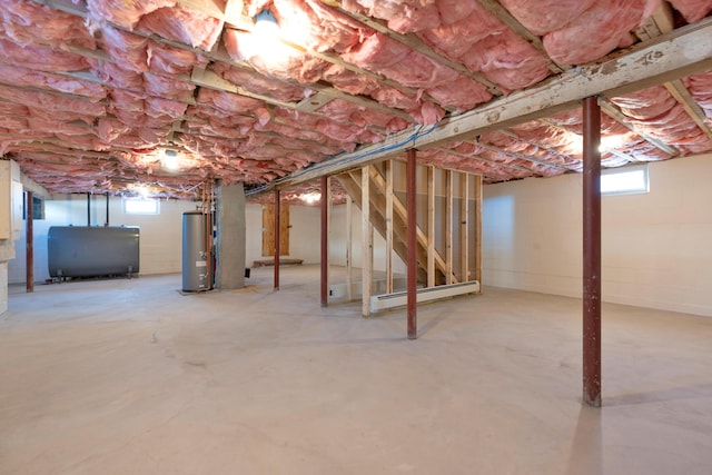 basement with a baseboard radiator, gas water heater, and a healthy amount of sunlight