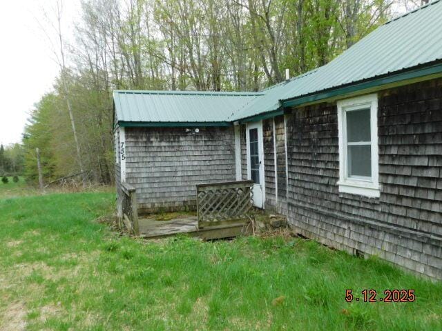 view of side of property featuring metal roof and a lawn
