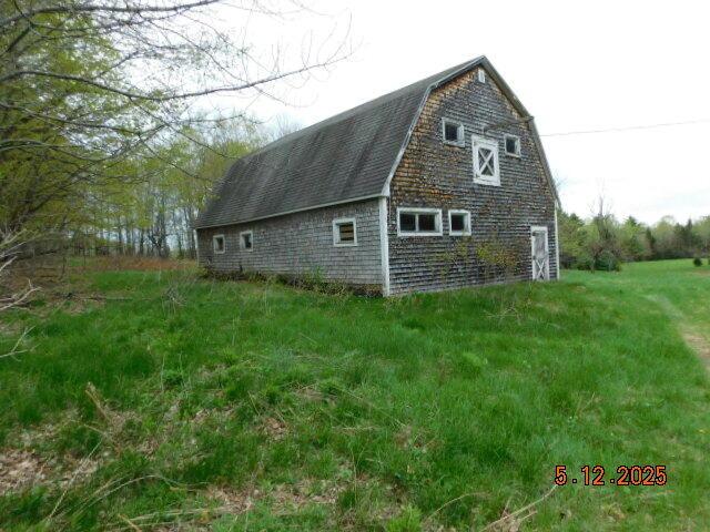 view of home's exterior with a barn, a gambrel roof, and an outbuilding