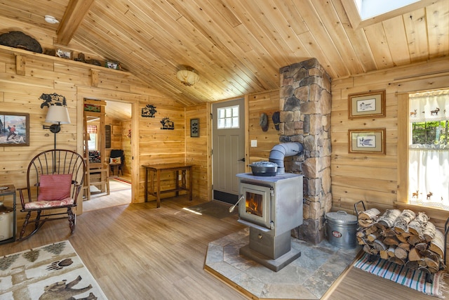 interior space featuring a wood stove, wood-type flooring, lofted ceiling with skylight, and wood ceiling