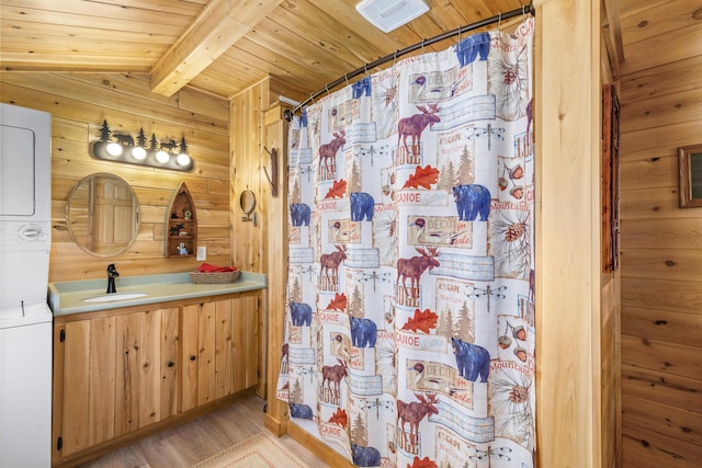 bathroom with wood walls, beamed ceiling, stacked washer and dryer, and wooden ceiling