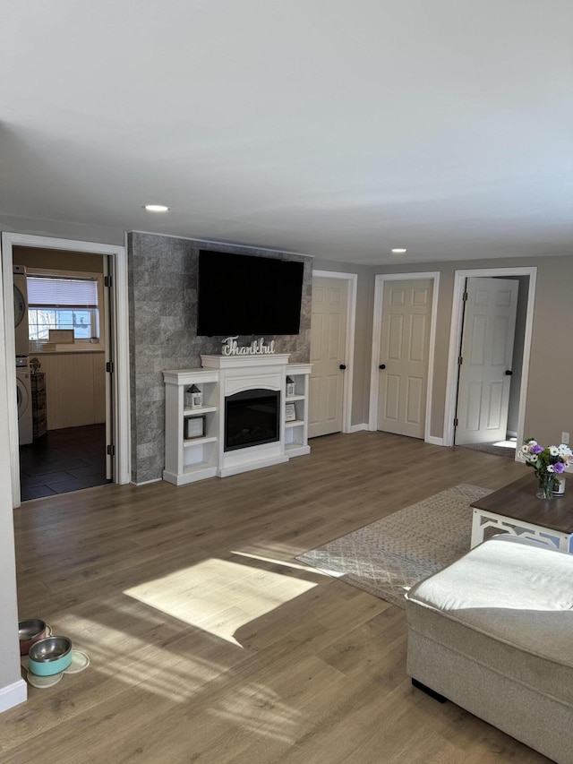 living room with a large fireplace, washer / clothes dryer, and hardwood / wood-style floors