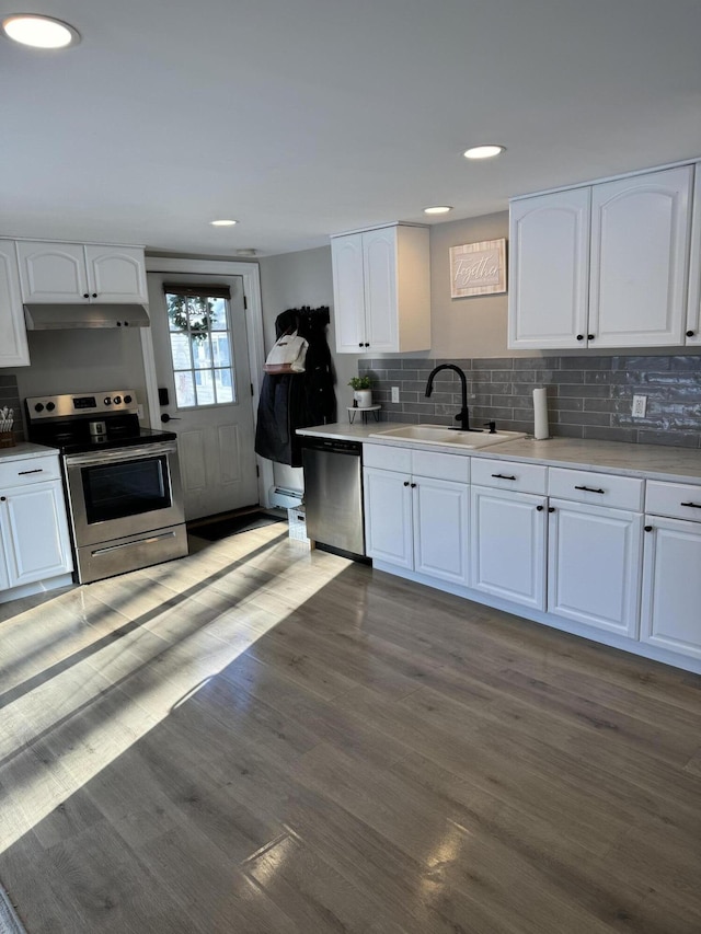 kitchen with stainless steel appliances, sink, dark wood-type flooring, and white cabinets