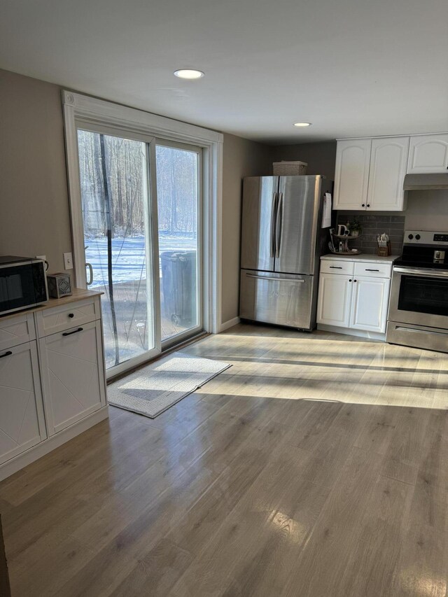 kitchen with white cabinetry, decorative backsplash, light hardwood / wood-style flooring, and appliances with stainless steel finishes