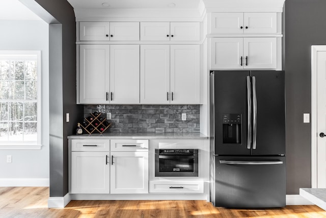 kitchen featuring black refrigerator with ice dispenser, white cabinetry, and wall oven