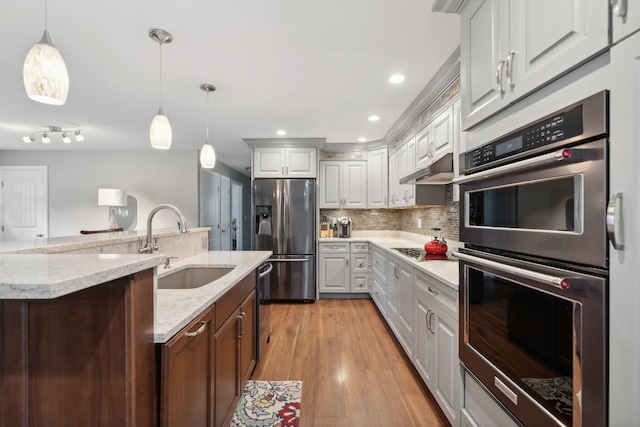 kitchen with pendant lighting, sink, appliances with stainless steel finishes, a kitchen island with sink, and white cabinets