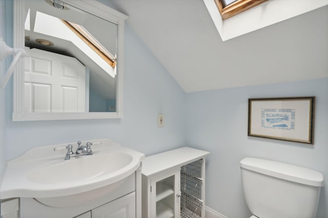 bathroom featuring vanity, vaulted ceiling with skylight, and toilet