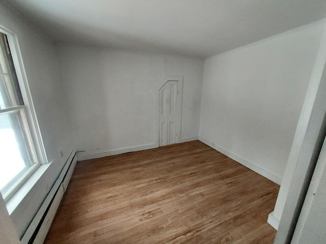 unfurnished room with baseboard heating and light hardwood / wood-style flooring