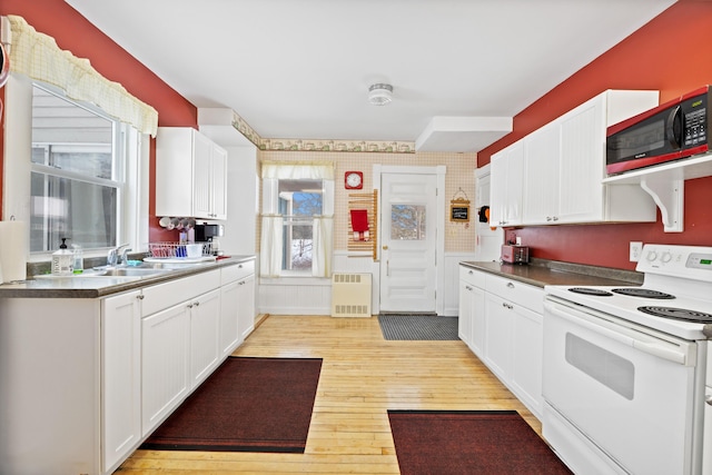 kitchen featuring white cabinetry, radiator, light wood-type flooring, and white range with electric cooktop