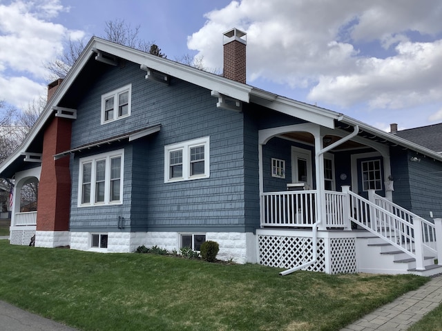 view of home's exterior featuring a lawn, covered porch, and a chimney