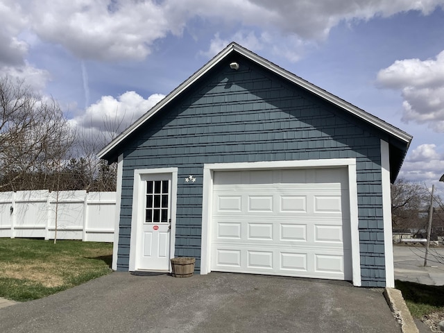 garage with aphalt driveway and fence