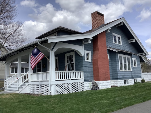 view of front of home with a front yard, a porch, and a chimney