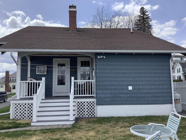 view of front of house with covered porch, a chimney, and a shingled roof