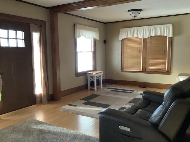 living area featuring crown molding, light wood-style flooring, and baseboards