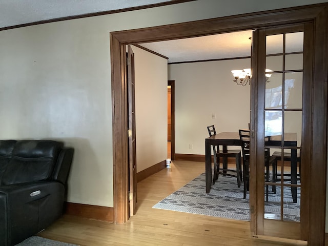 dining space featuring crown molding, a notable chandelier, light wood-style floors, and baseboards