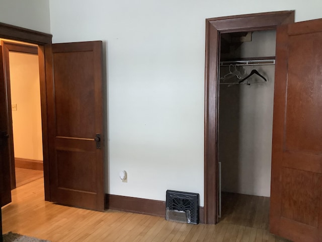 unfurnished bedroom featuring a closet, baseboards, a spacious closet, and hardwood / wood-style flooring