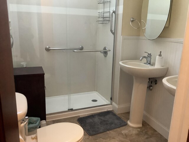 full bathroom with a wainscoted wall, toilet, and a stall shower