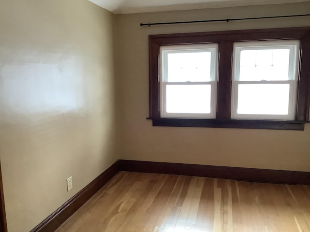 unfurnished room with light wood-type flooring and baseboards