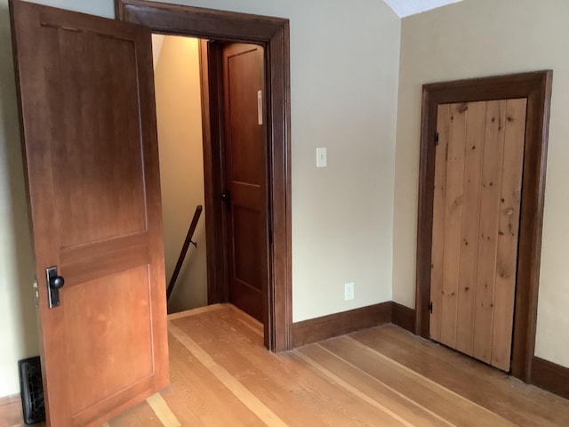 interior space with baseboards, an upstairs landing, and light wood-style floors