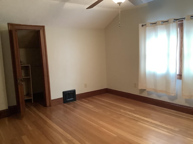 unfurnished bedroom with light wood finished floors, ceiling fan, baseboards, and lofted ceiling