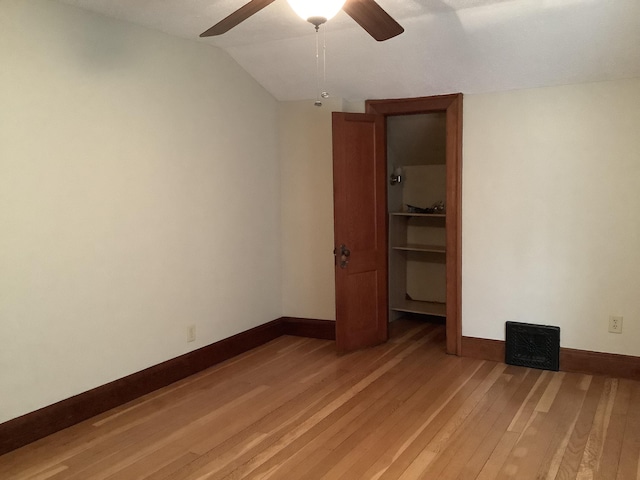 unfurnished bedroom with light wood finished floors, a closet, lofted ceiling, and baseboards