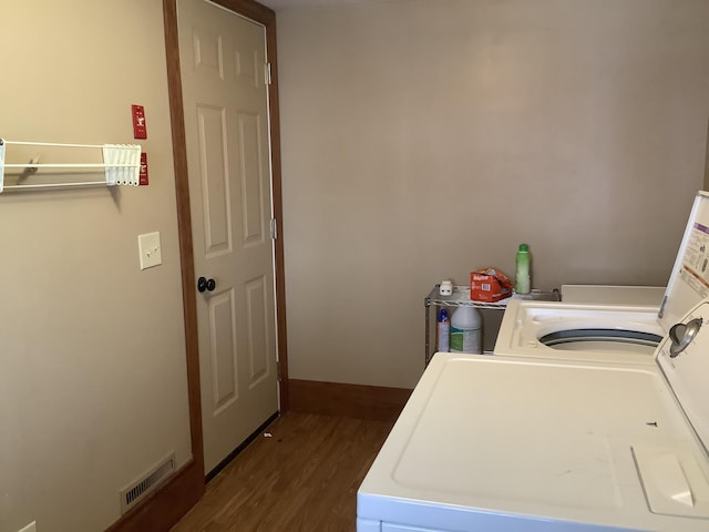 washroom featuring laundry area, washing machine and dryer, visible vents, and dark wood-style flooring