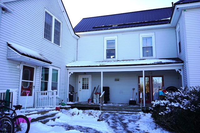 snow covered house featuring a porch