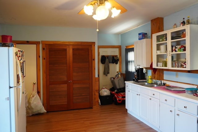 kitchen featuring white fridge, white cabinets, light wood-type flooring, sink, and ceiling fan