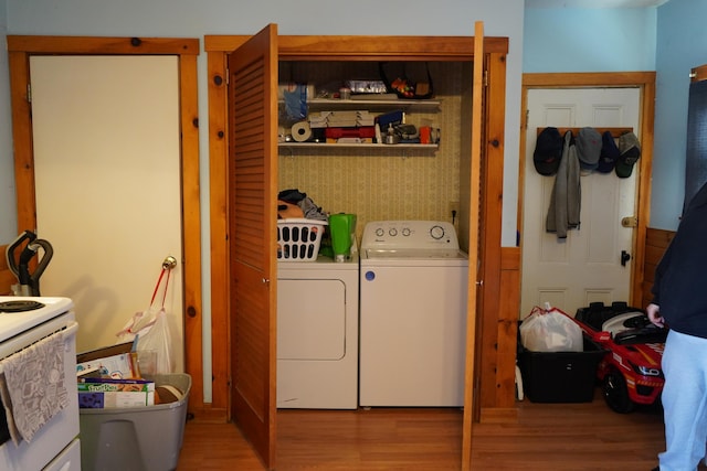 clothes washing area with washer and clothes dryer and light wood-type flooring