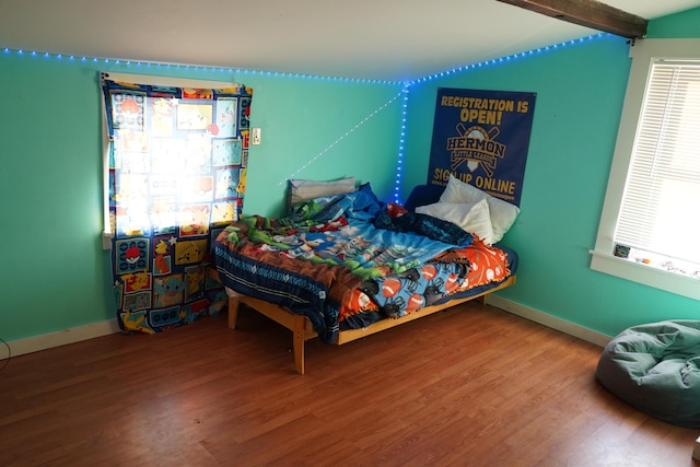 bedroom with hardwood / wood-style flooring and beamed ceiling