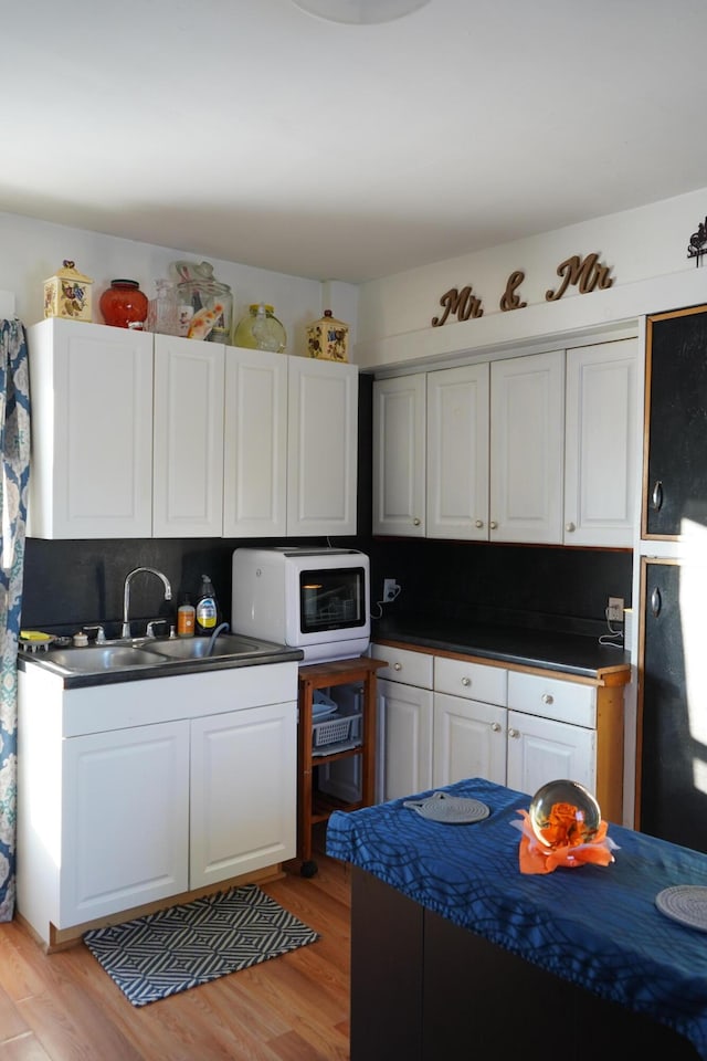 kitchen with sink, white cabinetry, light hardwood / wood-style floors, and tasteful backsplash