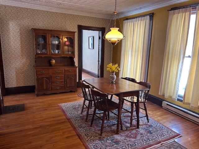 dining space featuring hardwood / wood-style floors, ornamental molding, and a healthy amount of sunlight