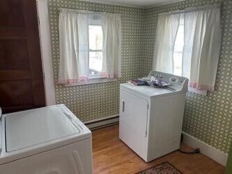 laundry room with light hardwood / wood-style flooring, independent washer and dryer, and baseboard heating