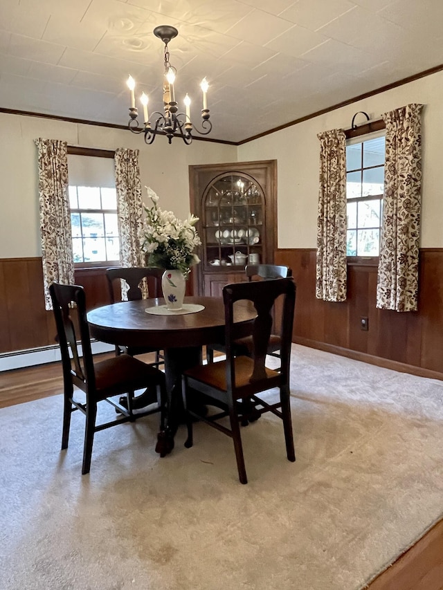 dining room with ornamental molding, wood walls, a healthy amount of sunlight, and an inviting chandelier