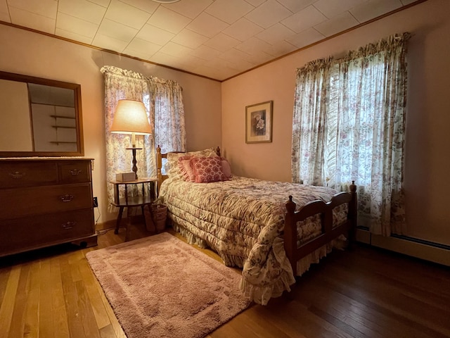 bedroom featuring hardwood / wood-style flooring, ornamental molding, and multiple windows