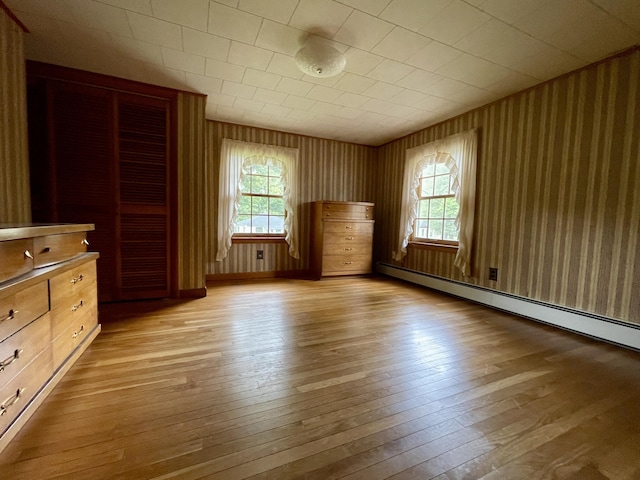 unfurnished bedroom featuring light hardwood / wood-style floors, a baseboard radiator, and multiple windows