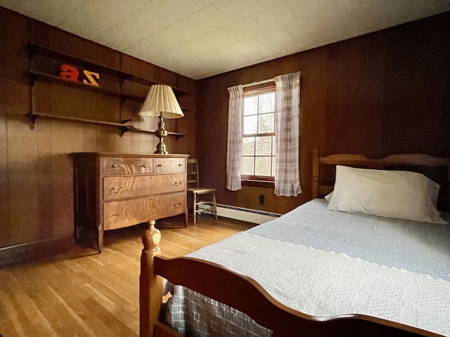 bedroom featuring wood-type flooring, wood walls, and baseboard heating