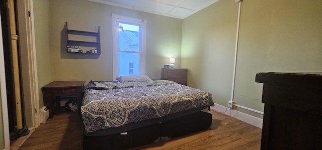 bedroom with ornamental molding and wood-type flooring