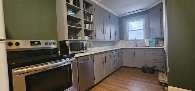 kitchen featuring appliances with stainless steel finishes, sink, gray cabinetry, ornamental molding, and light hardwood / wood-style flooring