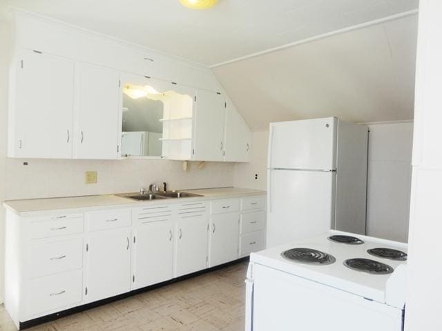 kitchen with white cabinetry, sink, white appliances, and vaulted ceiling