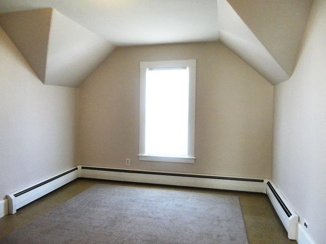 additional living space with lofted ceiling, dark carpet, and a baseboard radiator