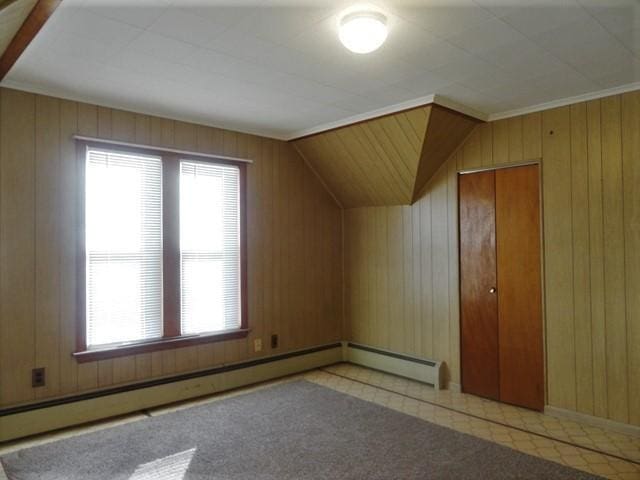 bonus room featuring a baseboard radiator, vaulted ceiling, and wooden walls