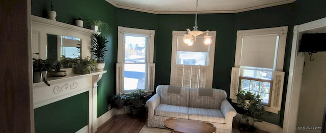 living area featuring hardwood / wood-style floors, crown molding, and an inviting chandelier