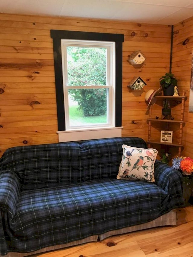 sitting room with hardwood / wood-style floors and wooden walls