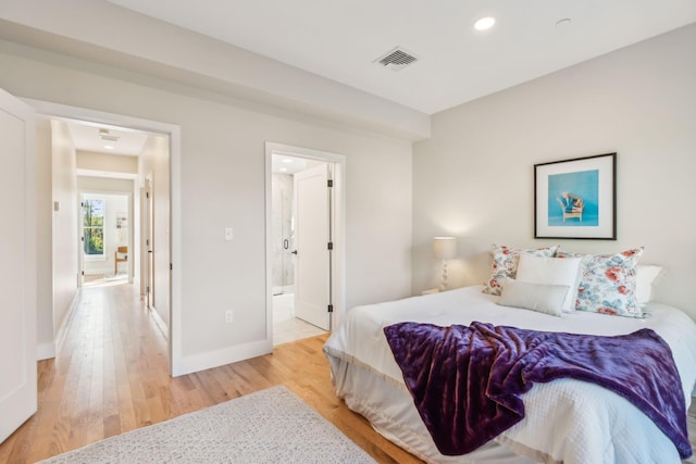 bedroom with ensuite bath and light hardwood / wood-style flooring