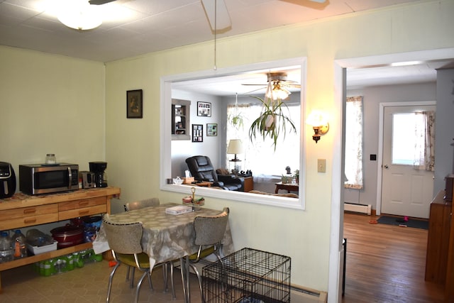 dining area featuring a baseboard heating unit, crown molding, dark wood-type flooring, and ceiling fan