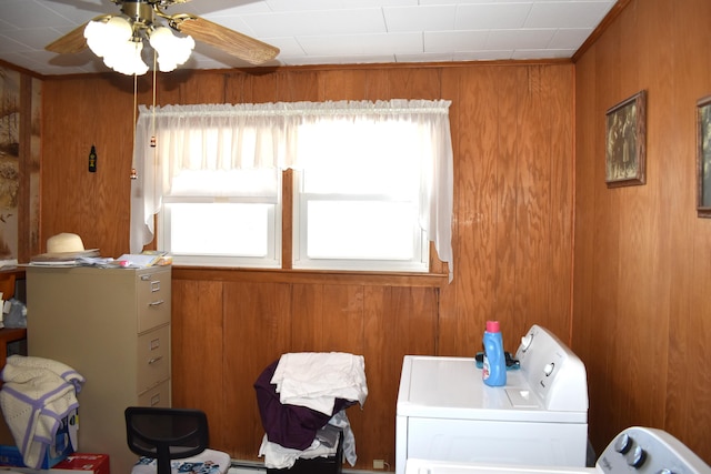 laundry area featuring ceiling fan, wooden walls, and washer and clothes dryer