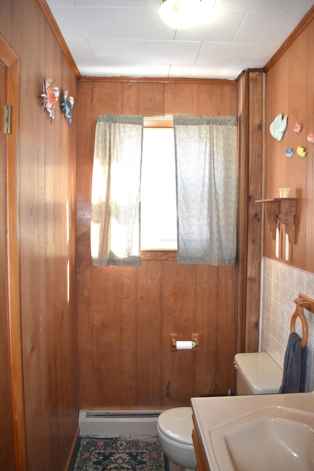 bathroom featuring sink, wooden walls, toilet, and baseboard heating