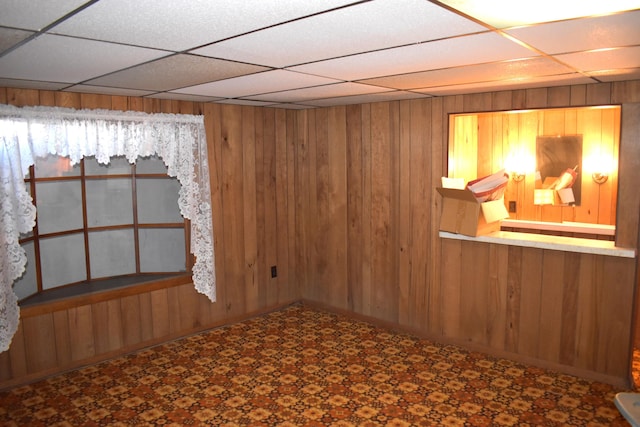 spare room featuring wooden walls and a drop ceiling